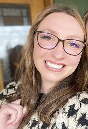 A woman in glasses smiling. 